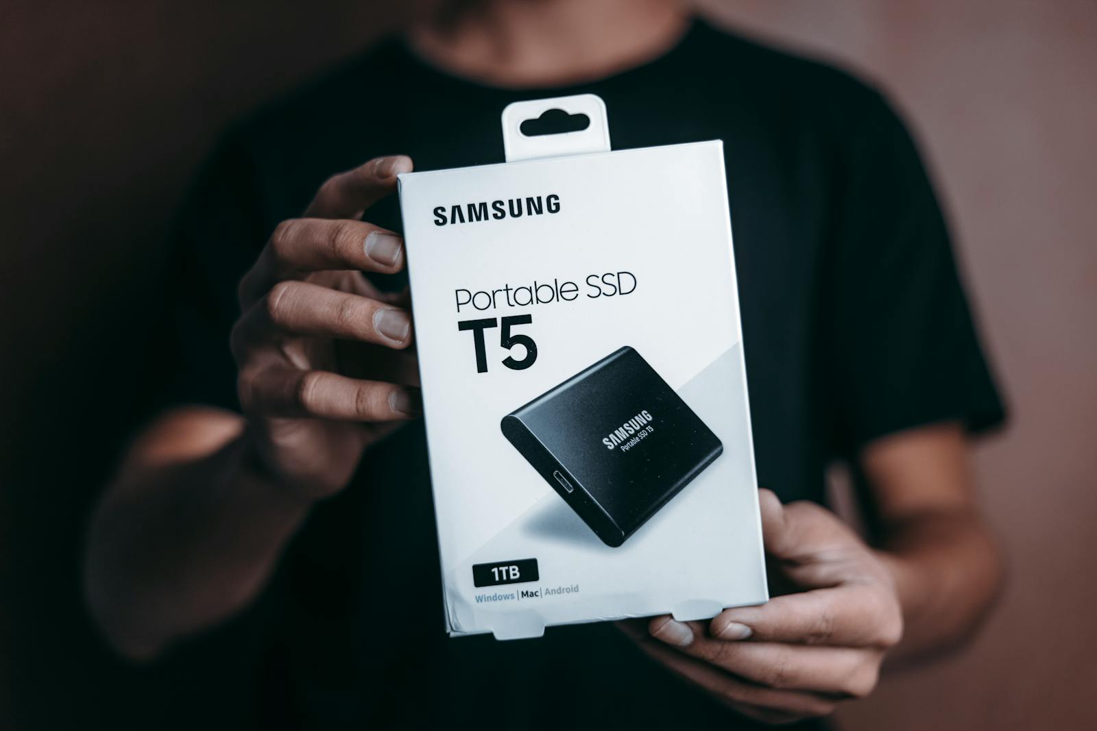 Person holding a Samsung Portable SSD T5 1TB in retail packaging — photo by Jibaro Foto on Pexels