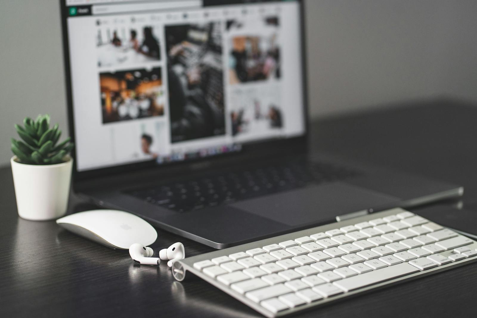 MacBook on a dark desk with Apple keyboard, magic mouse and AirPods — photo by Jean Daniel on Pexels