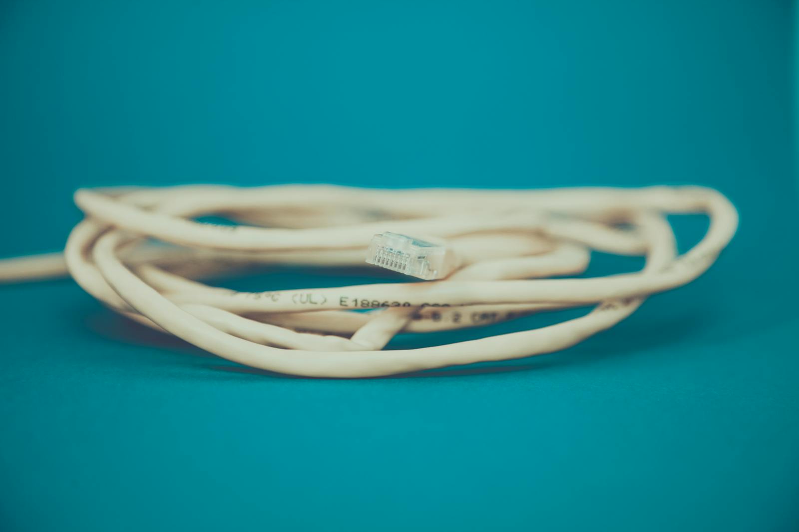 Coiled Ethernet cable on a teal background — photo by Markus Spiske on Pexels