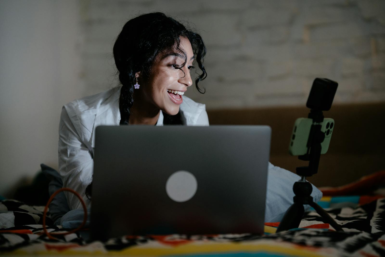 Person on a video call with a laptop and an iPhone on a tripod beside it — photo by Mizuno Kozuki on Pexels