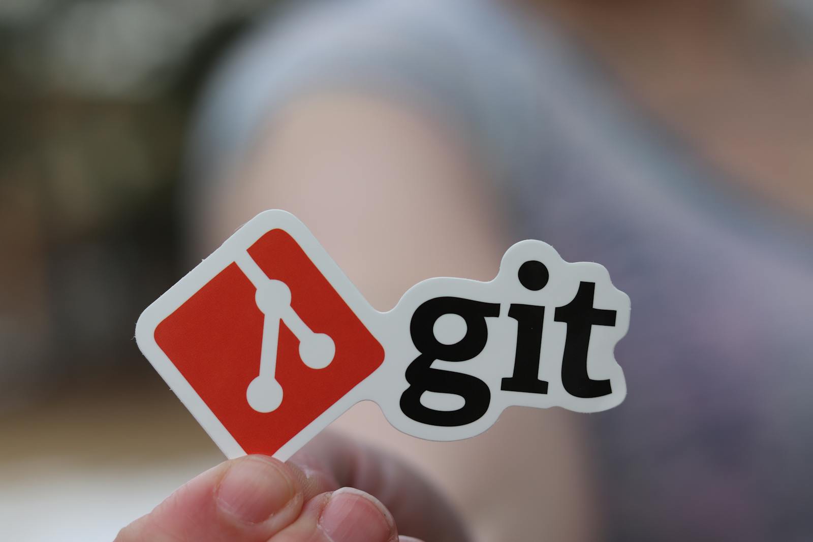Person holding a Git logo sticker — photo by Real Tough Candy on Pexels