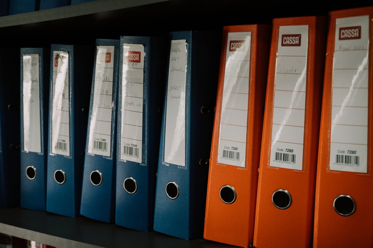 A row of blue and orange CASSA-brand office binders neatly stacked on a shelf — visual metaphor for plugin directories that look identical on the outside but may contain very different things inside (photo: zulfugarkarimov / Pexels)