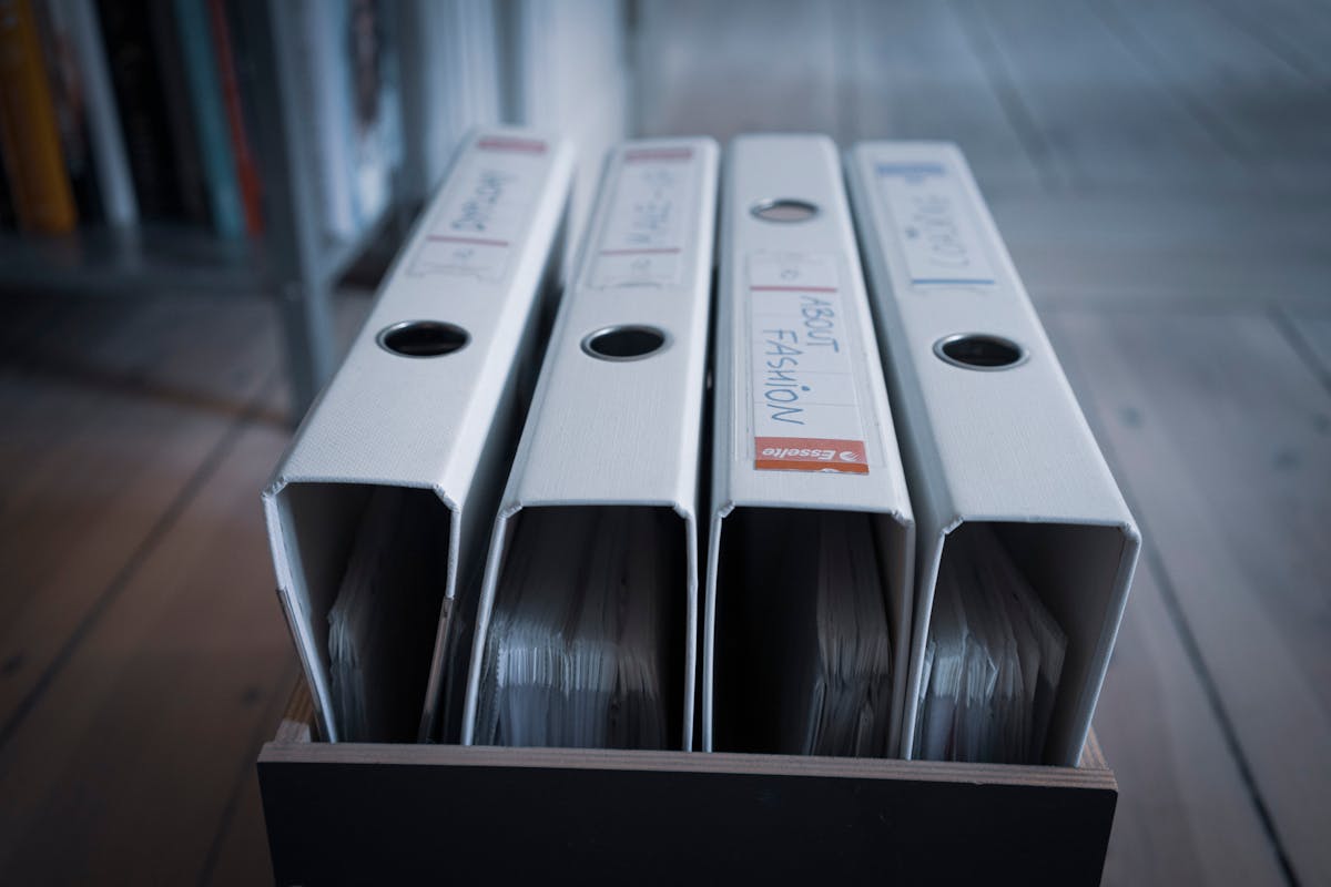 Four nearly identical white binders standing in a wooden box, suggesting how easy it is to overlook a slightly differently-named file in a directory listing (photo: Mateusz Dach / Pexels)