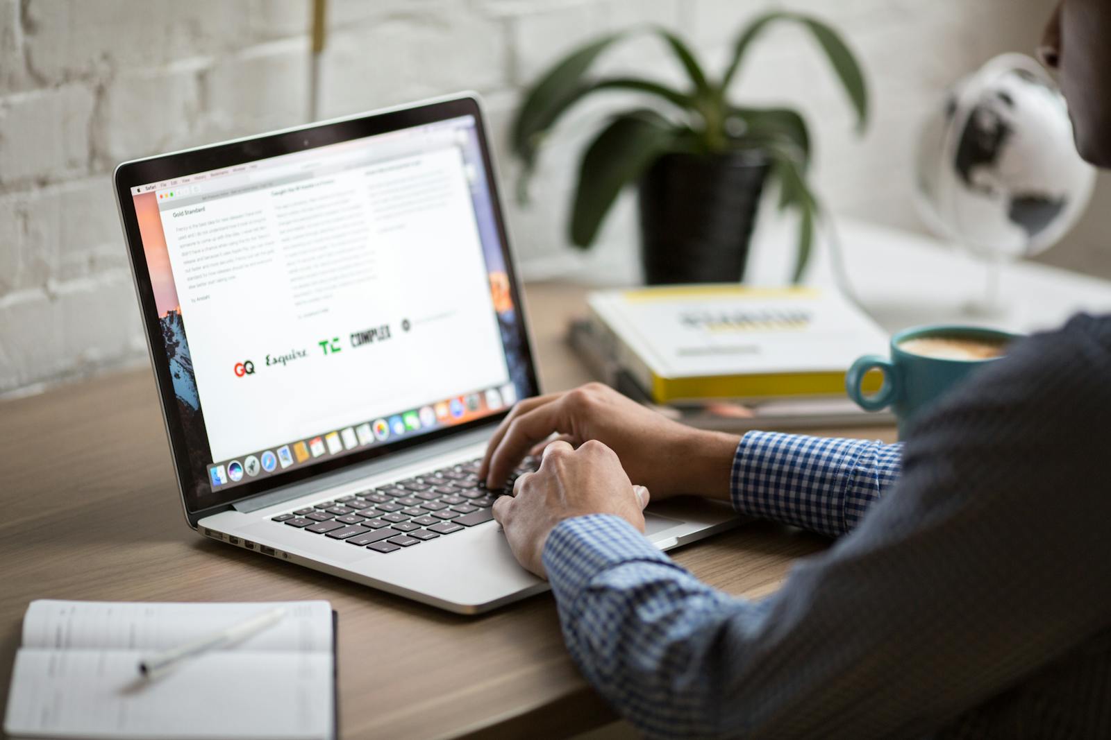 Hands typing on a MacBook with Safari open at a wooden desk with a coffee mug — photo by Burst on Pexels