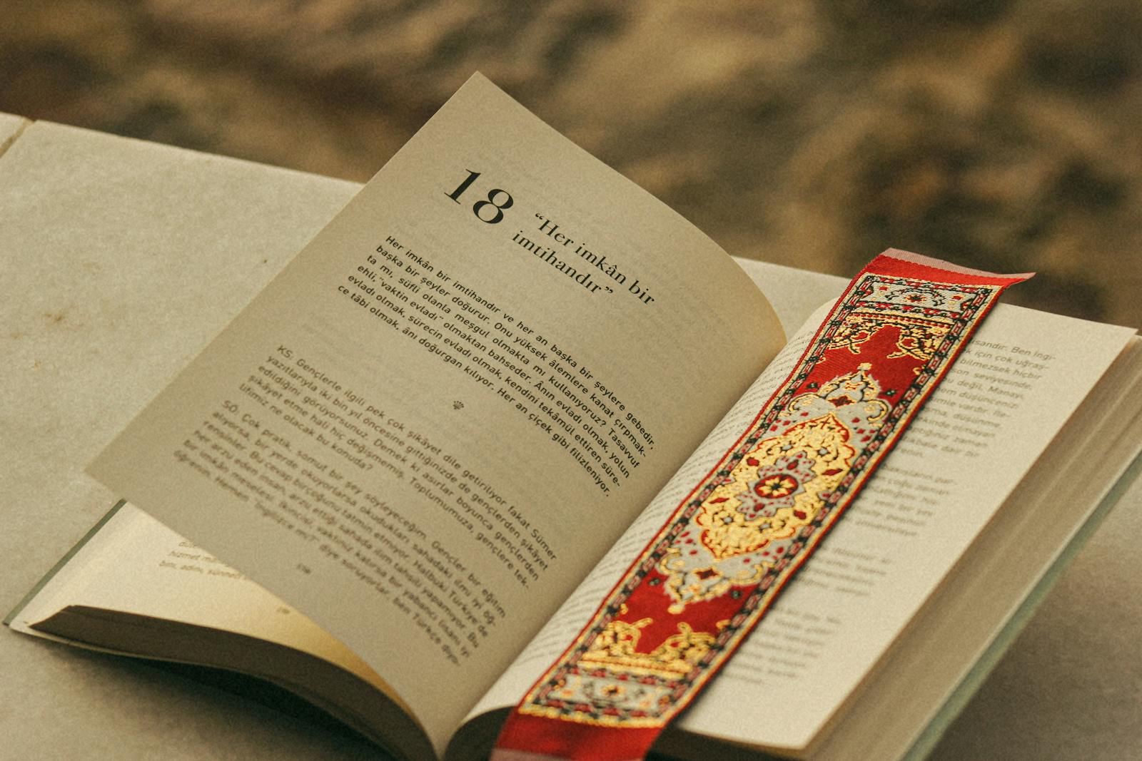 An open book with a decorative red and gold bookmark — photo by Feyza Ebrar on Pexels