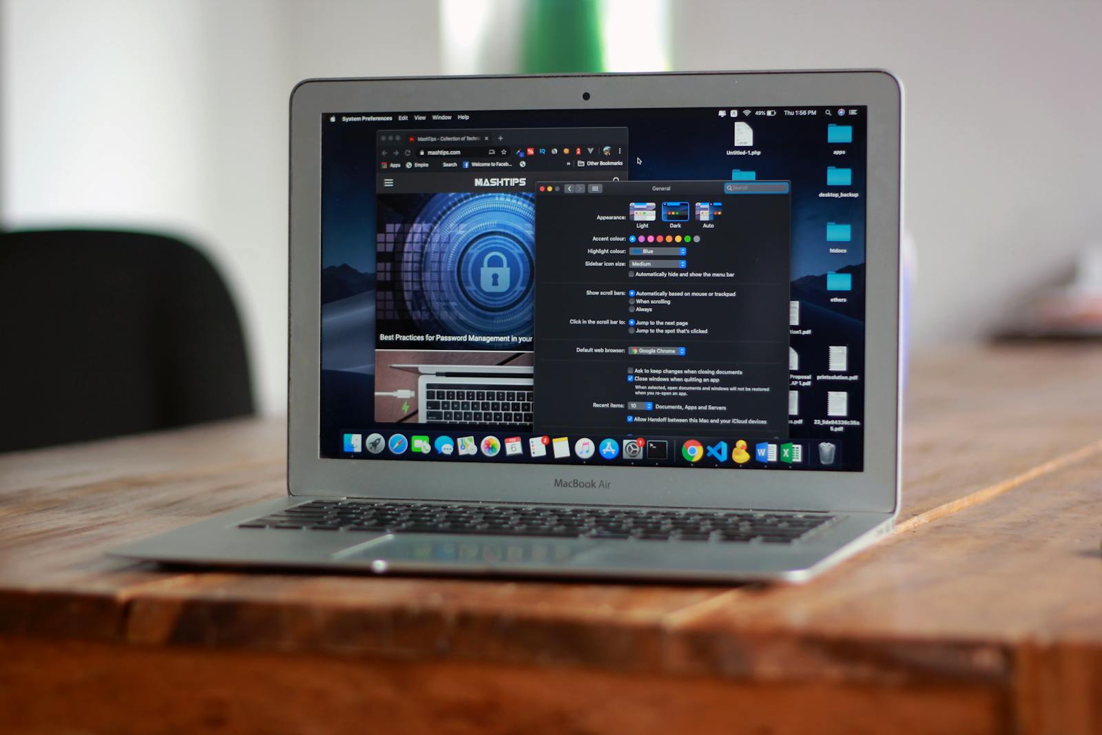 MacBook Air on a wooden desk with macOS System Preferences open and a folder of files visible — photo by abdullah-bin-mubarak on Pexels
