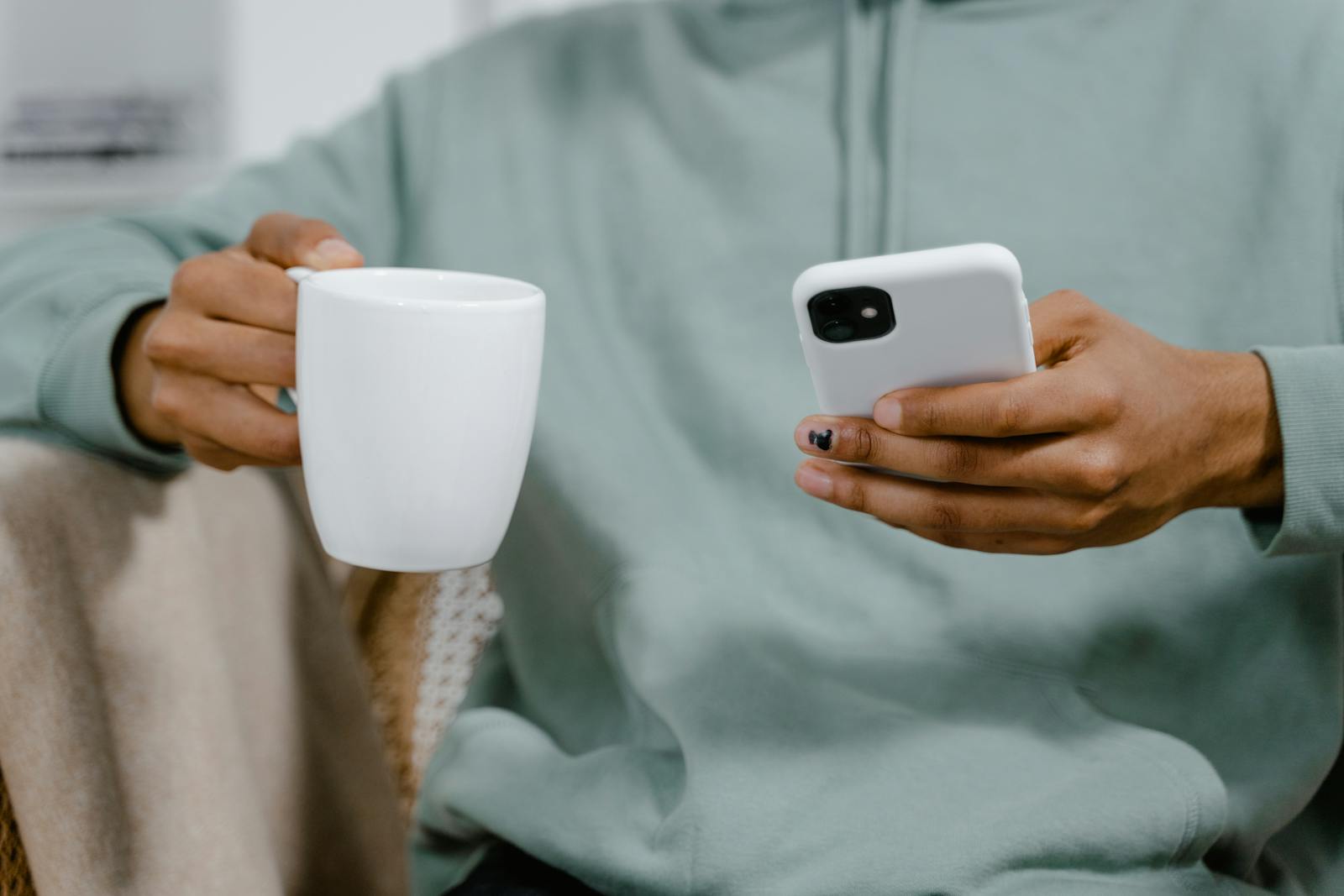 Hands holding a coffee mug and a smartphone — photo by Mart Production on Pexels