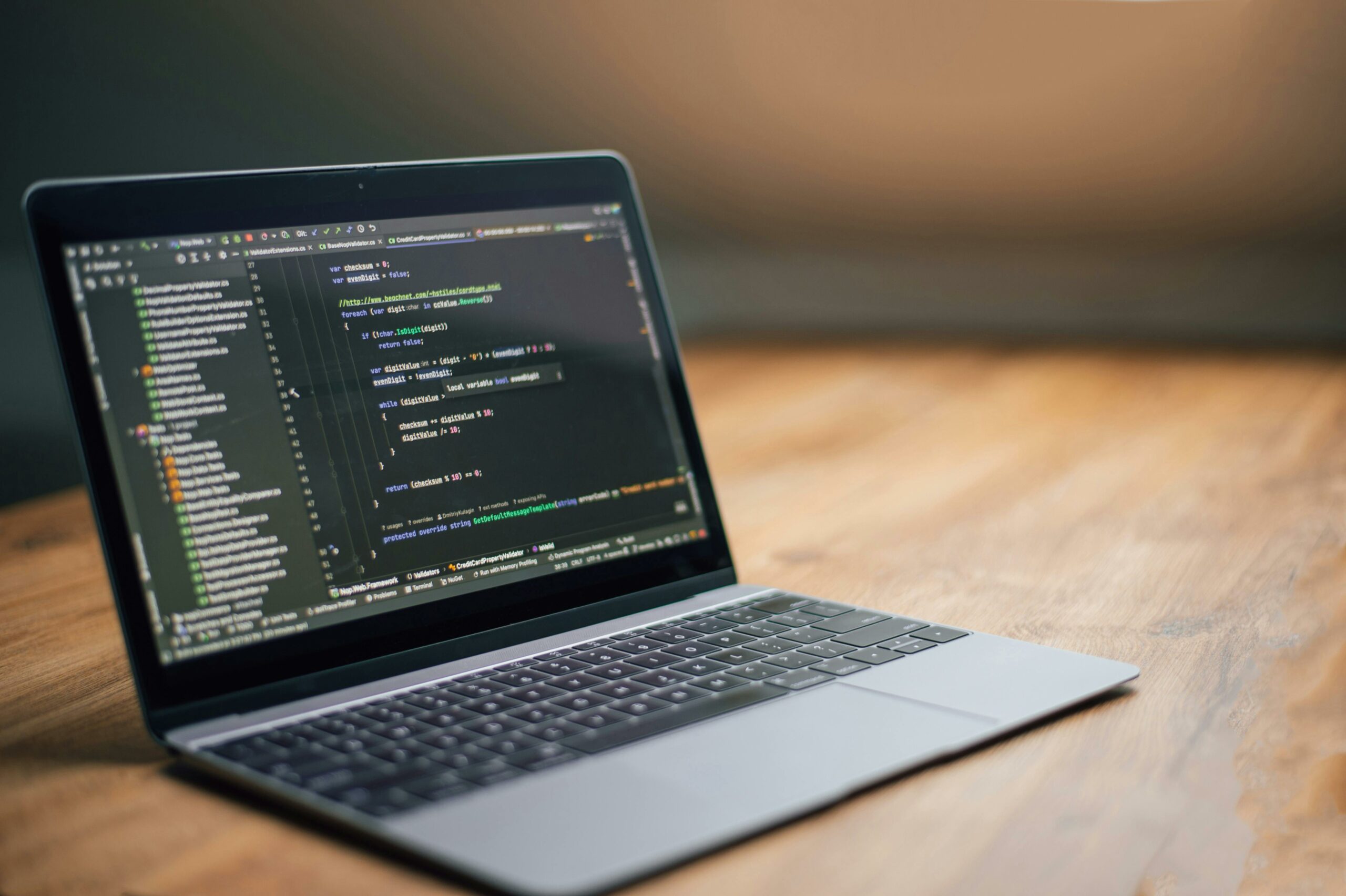 Laptop on a wooden desk showing source code in an editor — photo by dkomov on Pexels
