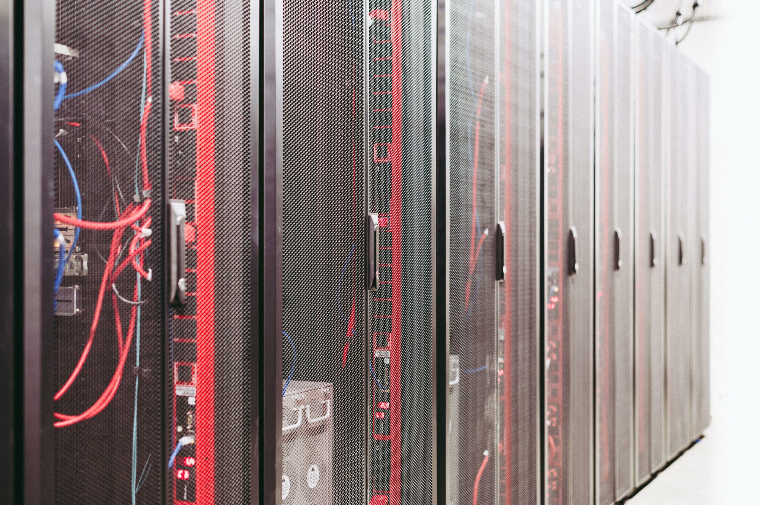 Server rack rows with mixed red and blue network cabling — photo by Brett Sayles on Pexels