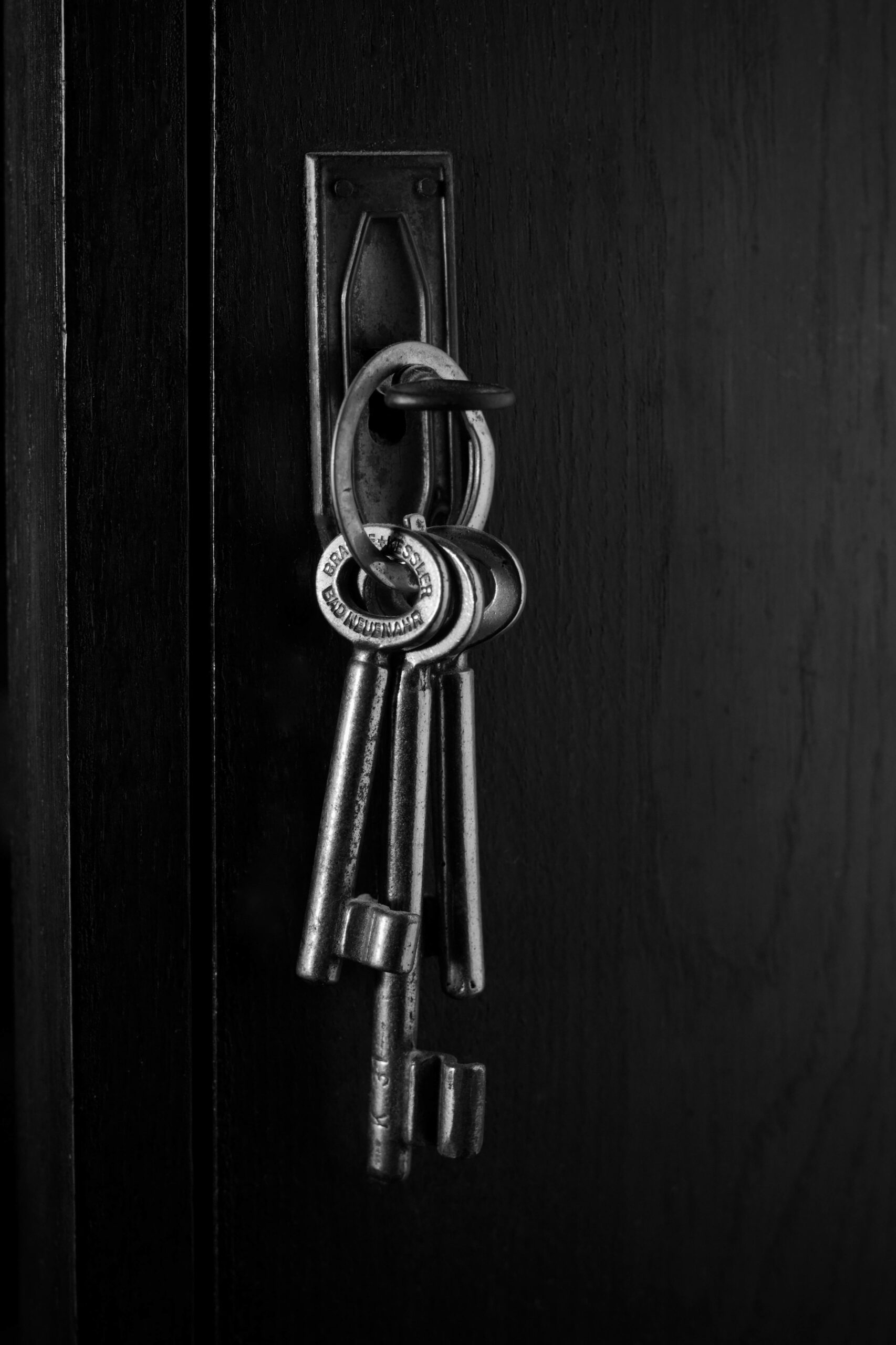 Bunch of vintage skeleton keys hanging from a dark door — photo by Peter Dyllong on Pexels