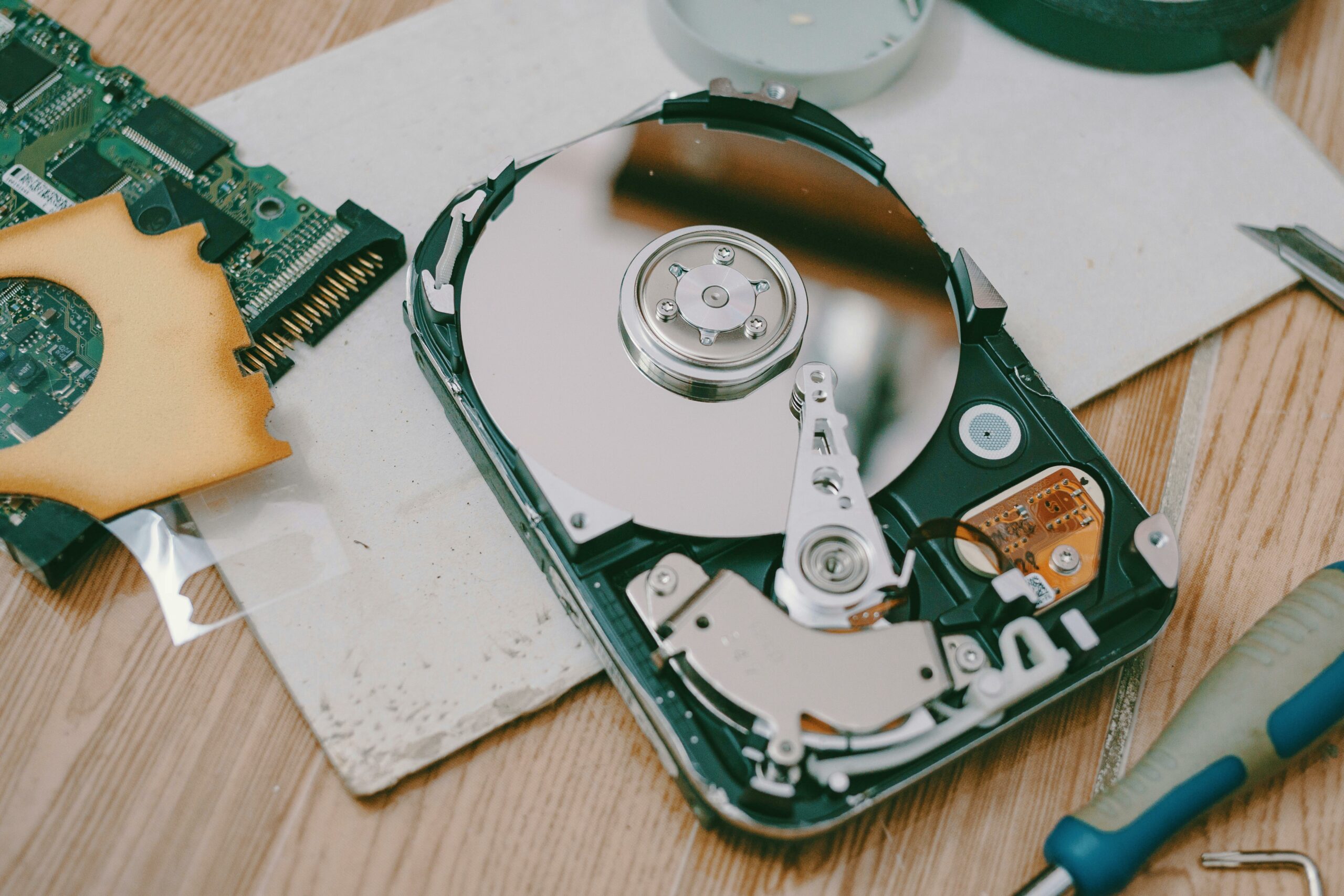 Disassembled hard drive with circuit board and tools — photo by Fox on Pexels