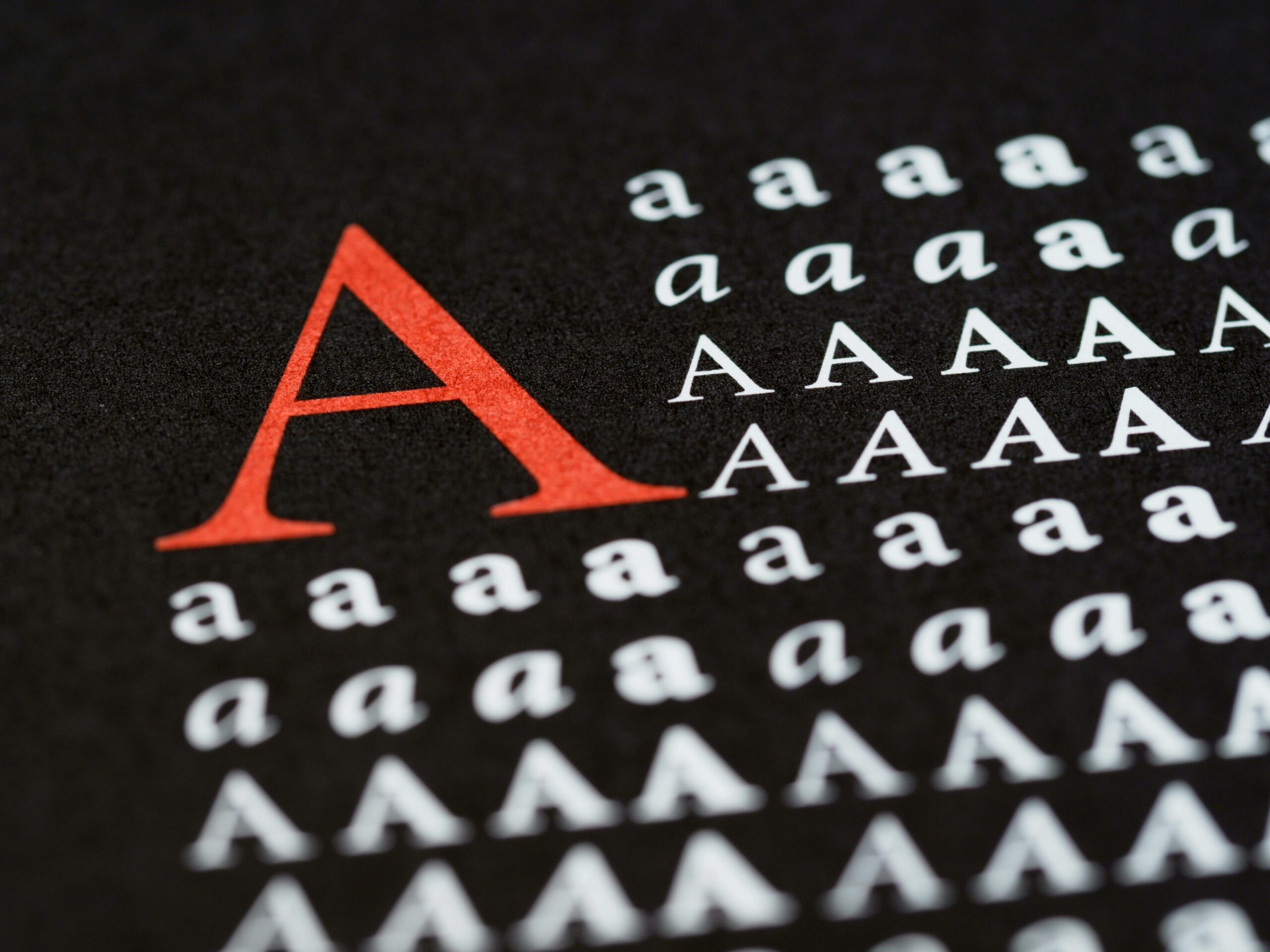 Black sheet with the letter A printed in different fonts and one bold red A — photo by Brett Jordan on Pexels