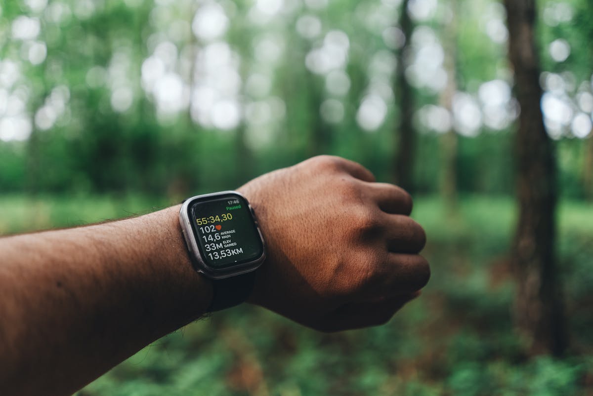 An Apple Watch on a runner's wrist showing pace and distance — photo by Omar Ramadan on Pexels
