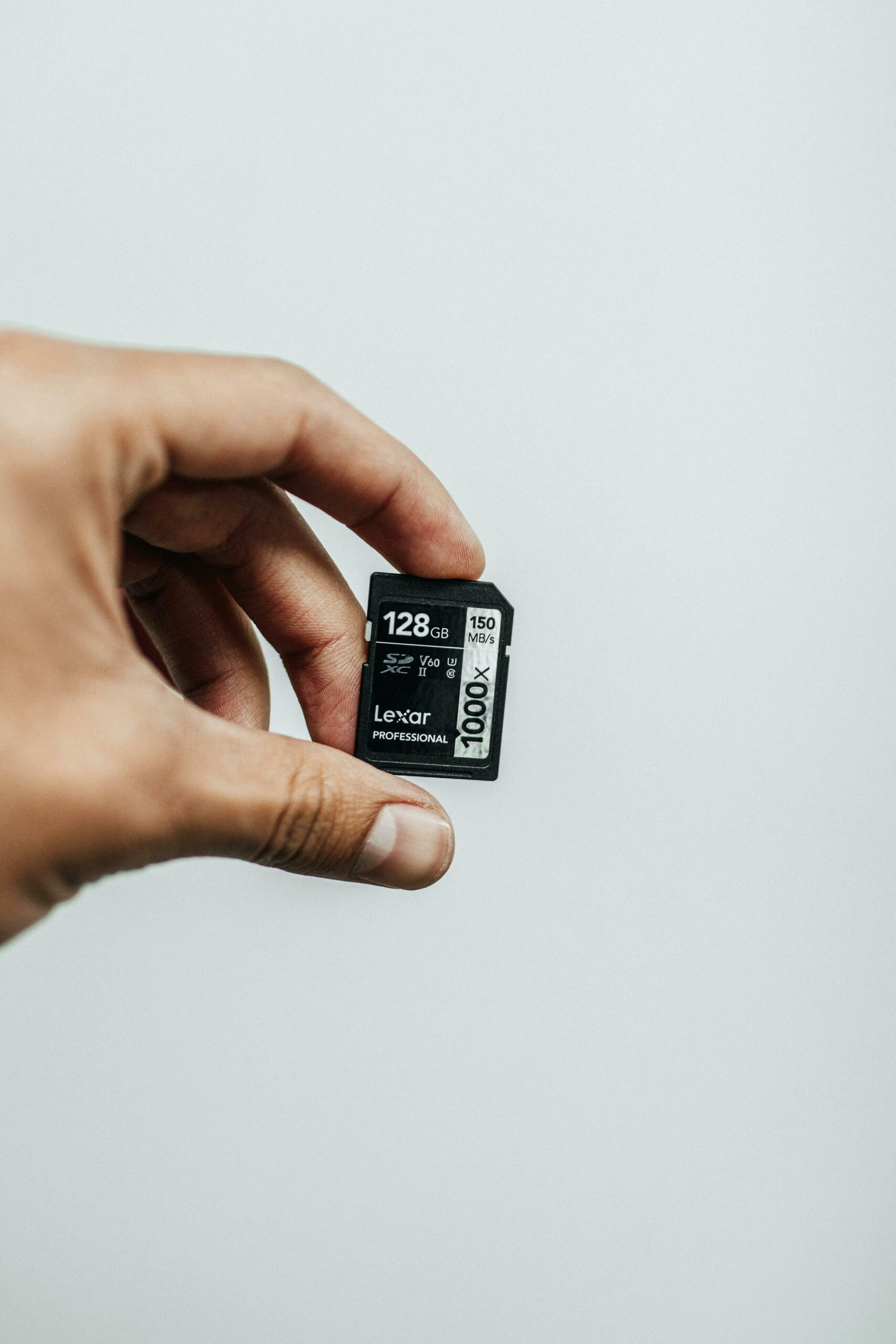Hand holding a 128 GB Lexar SDXC card — photo by jibarofoto on Pexels